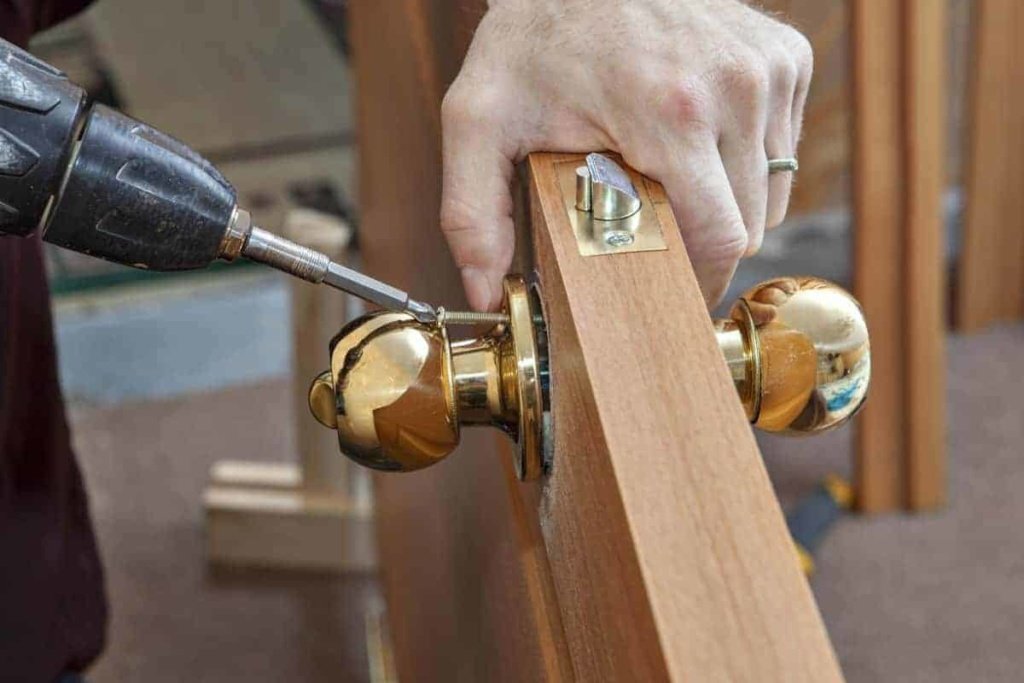 carpenter screwing door knob to door