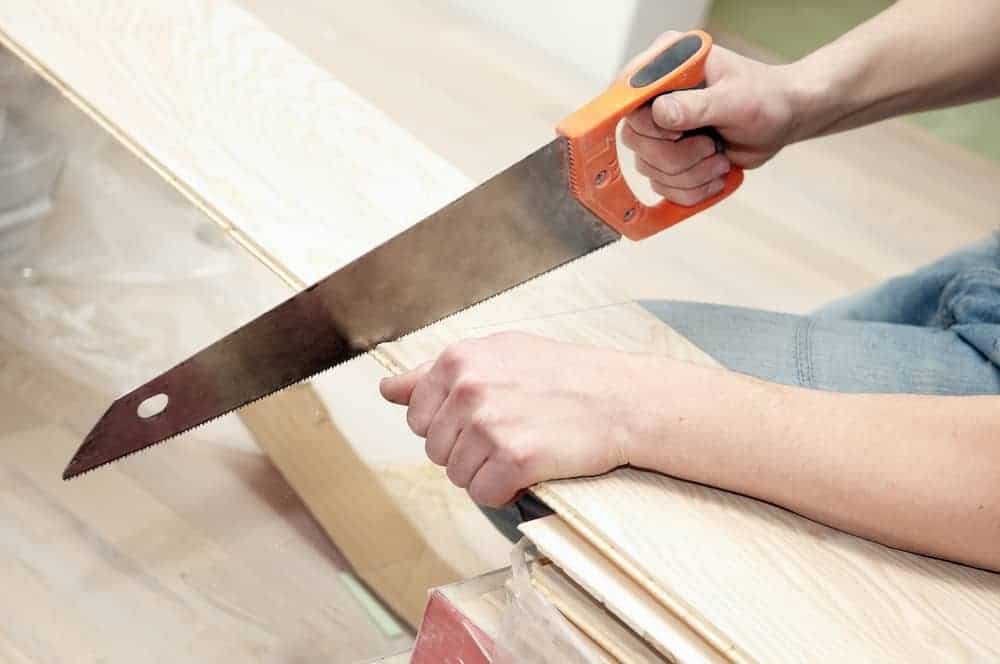man sawing blanks of wood with handsaw