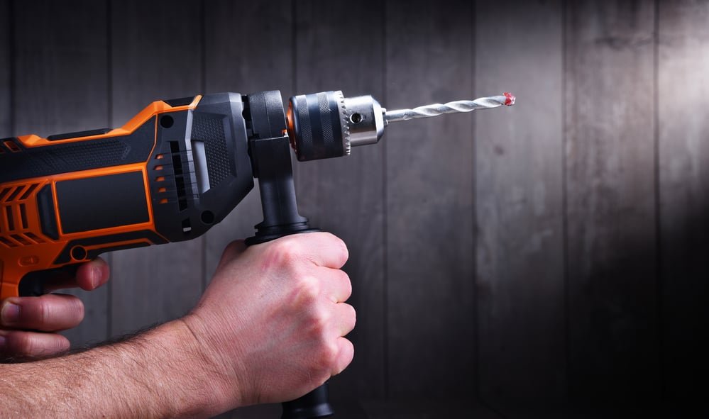a male looking hand holding a drill