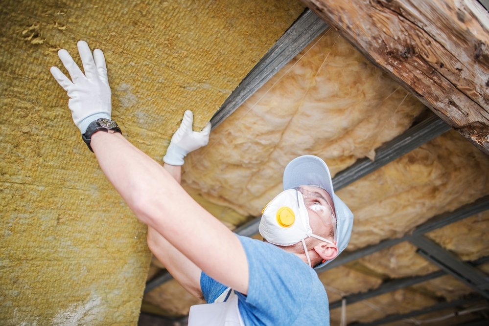 construction worker installing insulation material in the ceiling