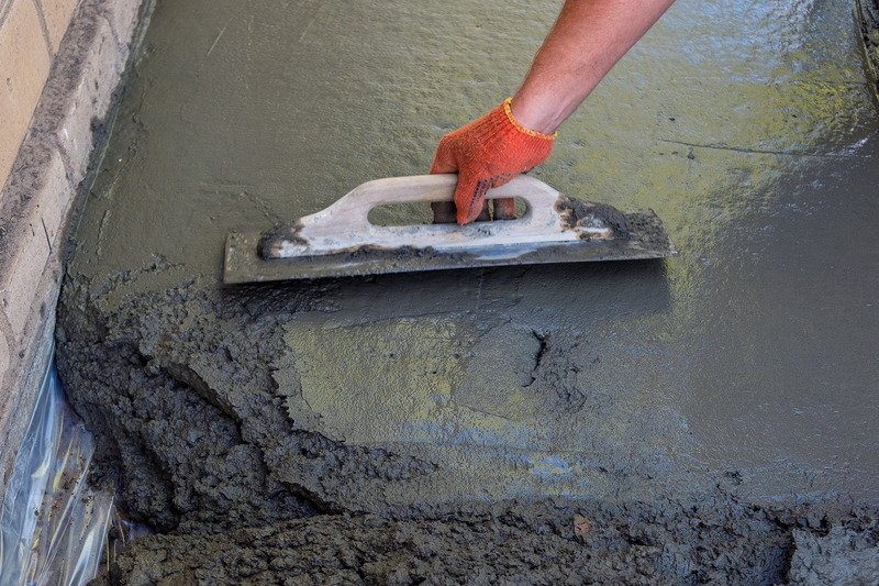 builder smoothing the surface of screed using a hand tool