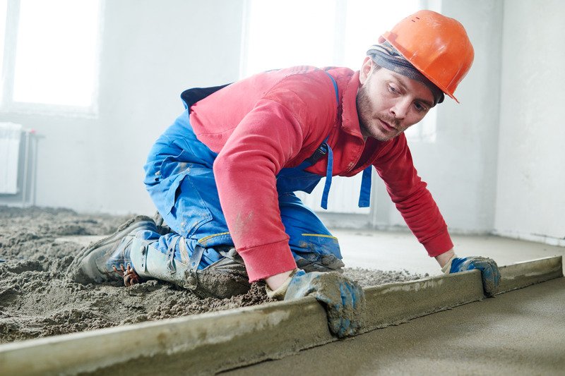 worker screeding a cement floor