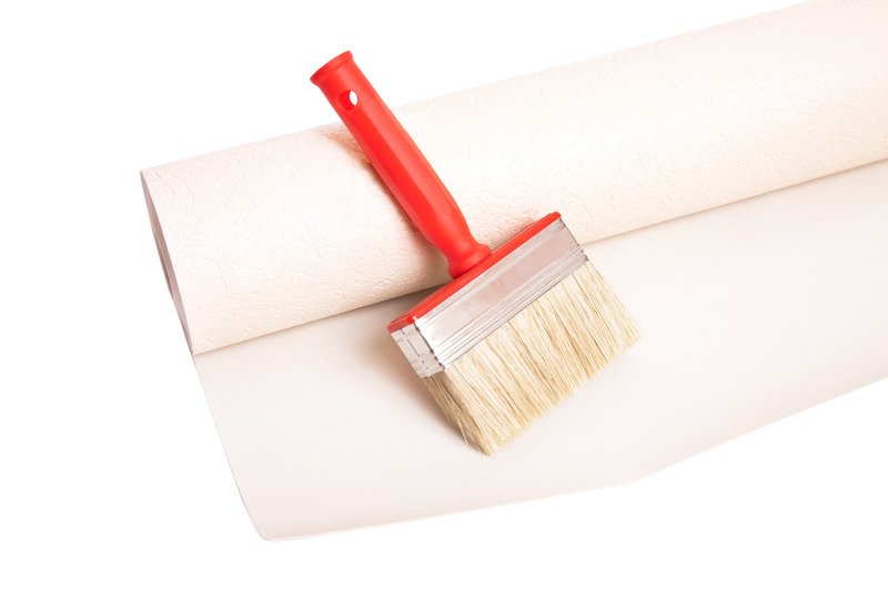 brush and roll of white wallpaper on white background