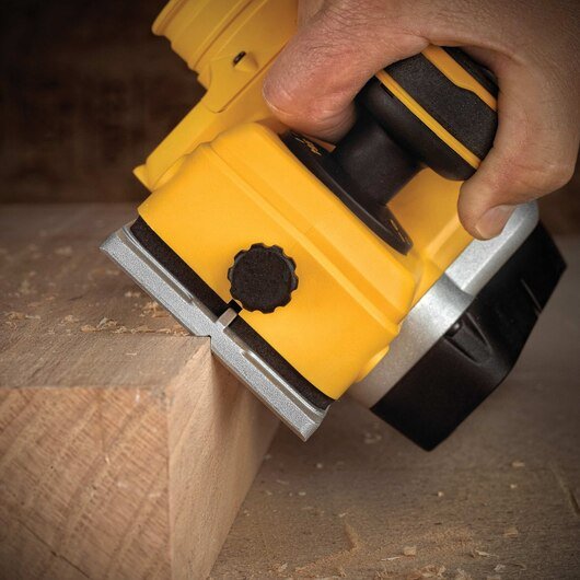 man using electric planer on the edge of a block of wood
