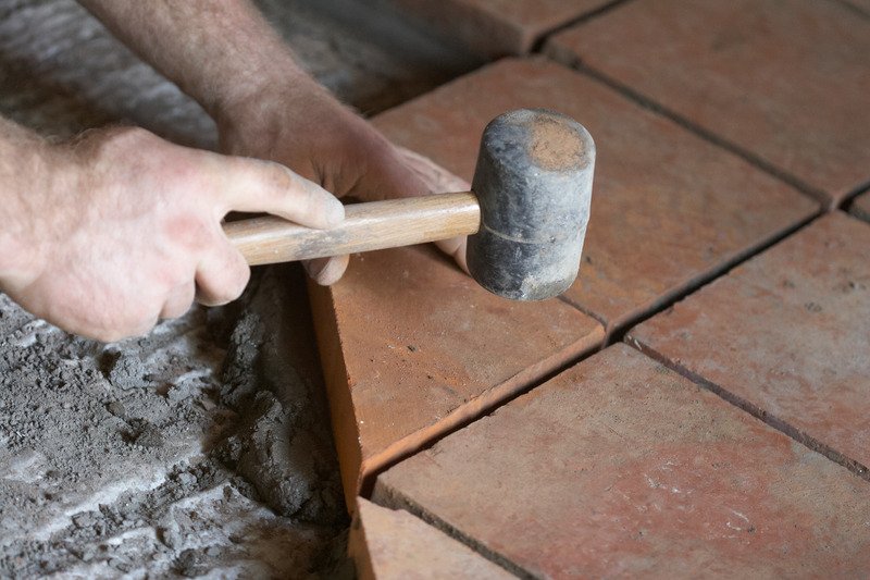 builder using a mallet to lay tiles