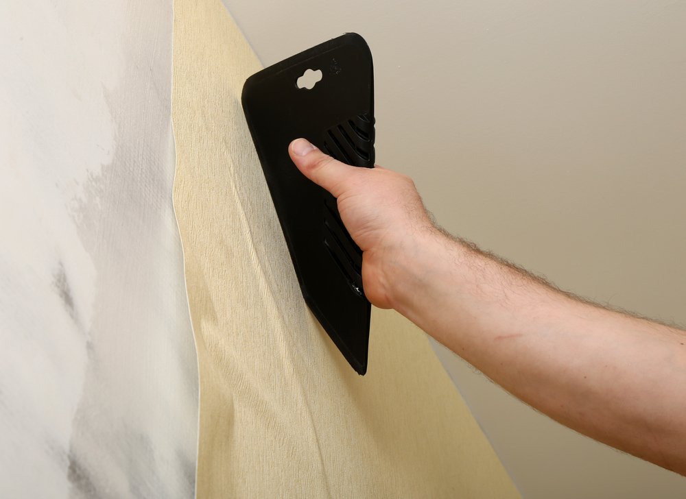 man hanging wallpaper using spatula