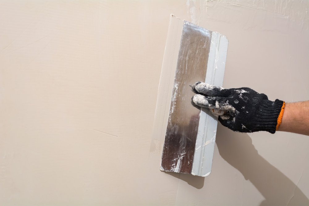 worker applying skim coat on a wall