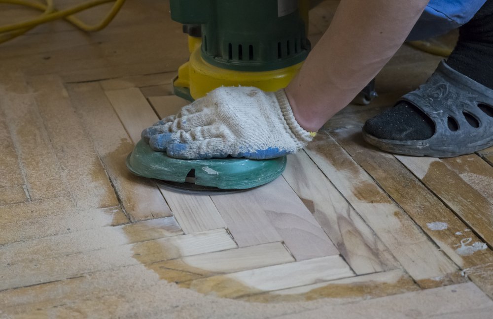 carpenter removing the coating from wooden floor