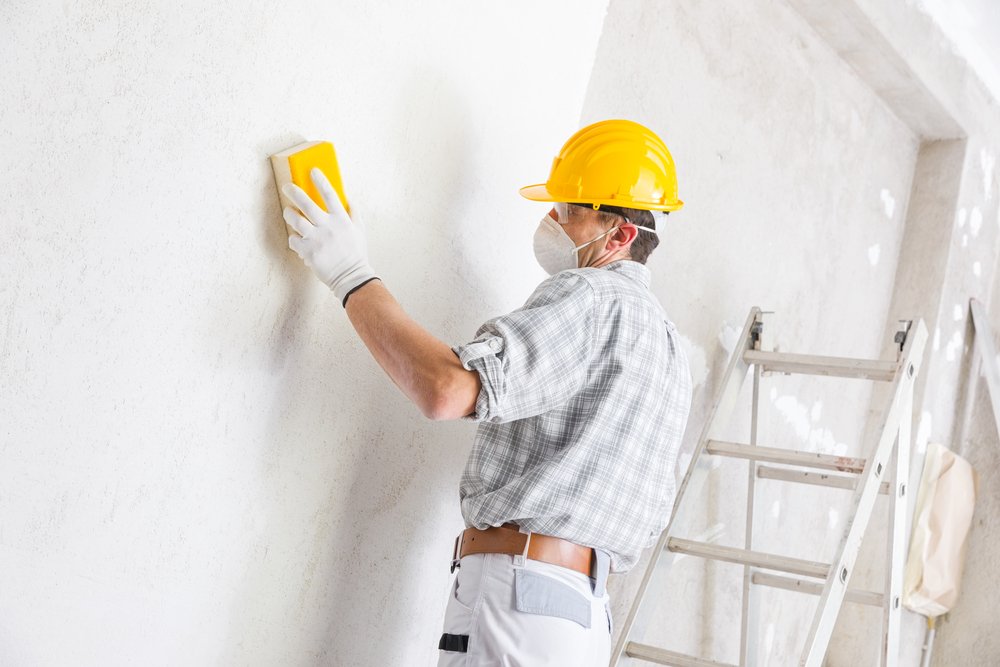 plasterer smoothing freshly plastered wall
