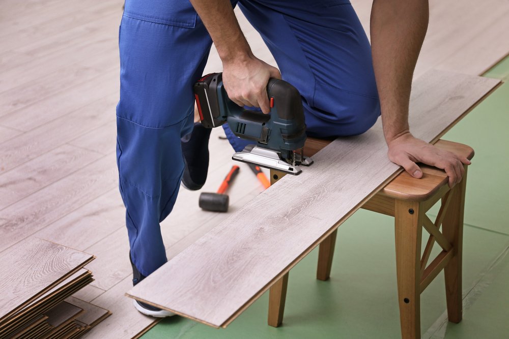 carpenter cutting laminate wood flooring with jigsaw