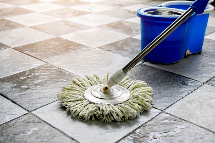 mop and blue bucket on a tiled floor