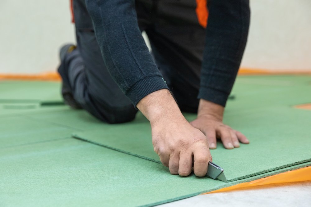 carpenter cutting underlayment for flooring