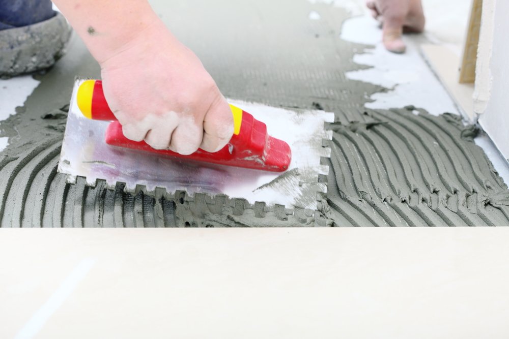 tiler spreading tile adhesive with a trowel
