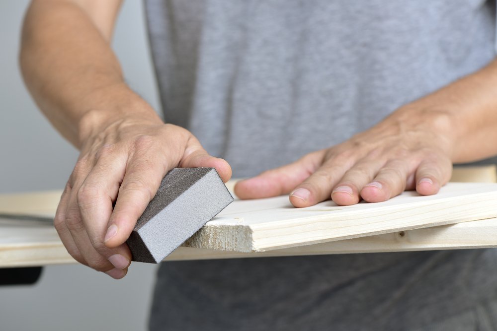 carpenter sanding edges of a wooden board