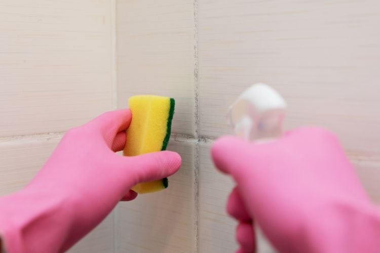 painter cleaning tiles using spray bottle and scrub before painting