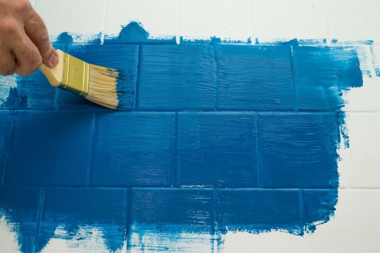 painter painting tiles blue using hand brush
