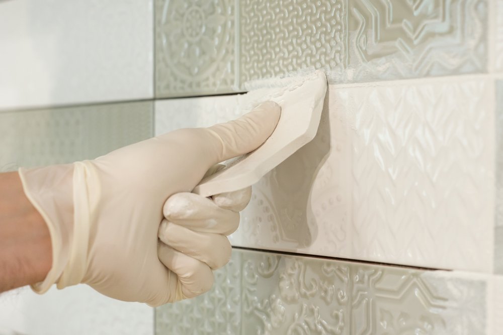 tiler applying grout on decorative tiles
