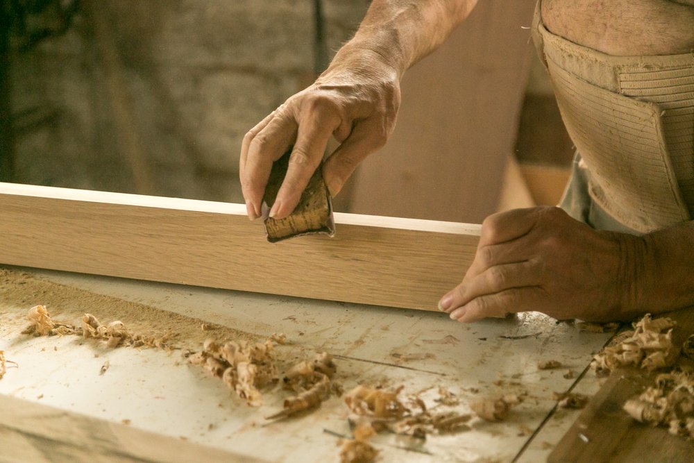 carpenter sanding wood using sandpaper