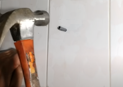 carpenter inserting wall plug into tile using hammer
