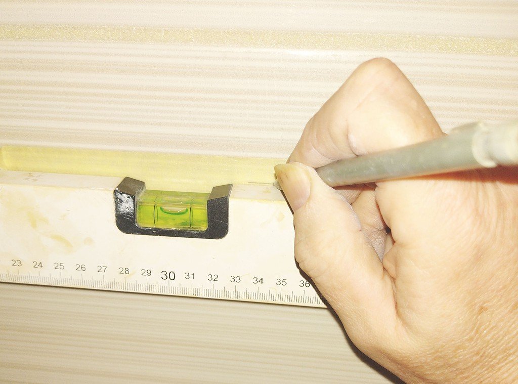 carpenter marking tiles using pencil and level bar