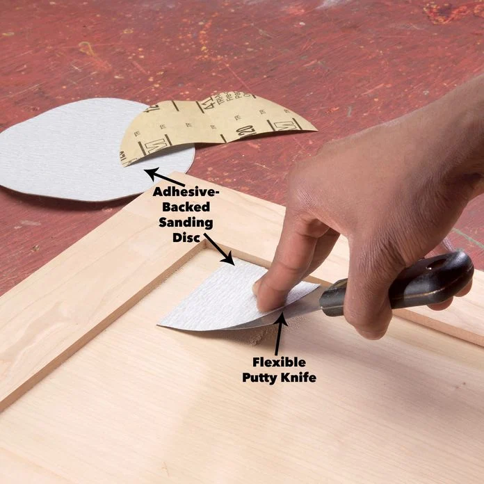 carpenter sanding wood using putty knife with adhesive sanding disc