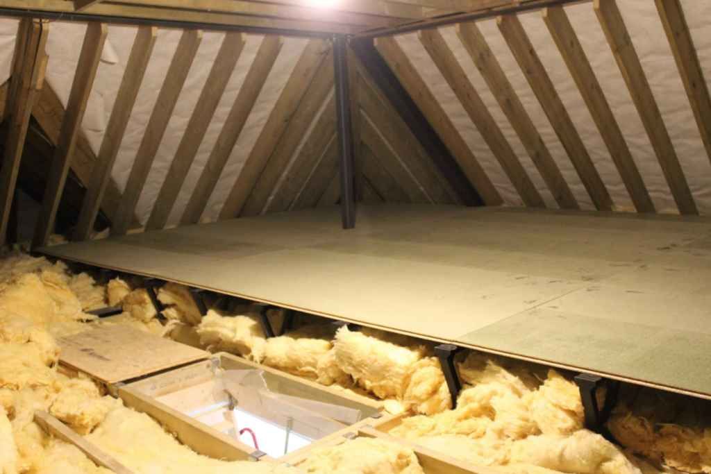 yellow insulation half covered by loft boards in the attic