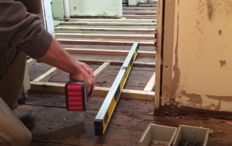 builder inserting decking screw on the wooden floor