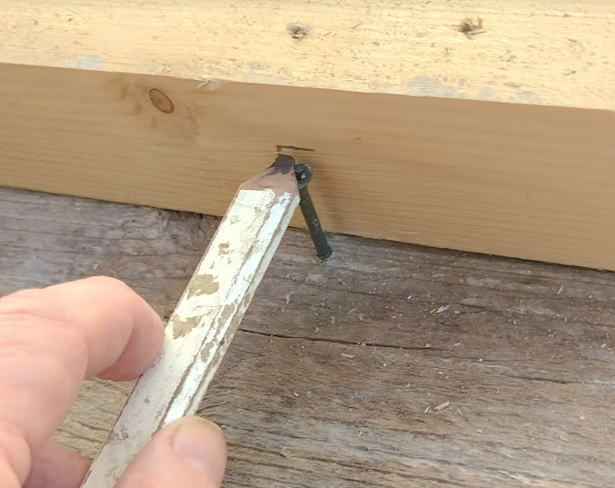 builder marking screw head on batten