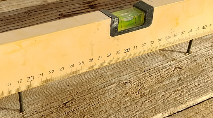 levelling screws on a wooden floor using a spirit level